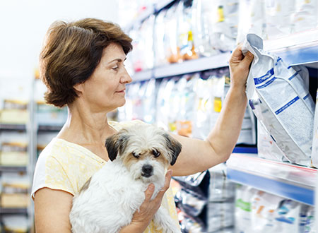 woman selecting dog food bag from shelf